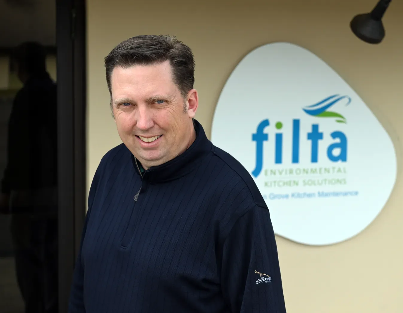 A person looking direct at camera while smiling with Filta logo in background